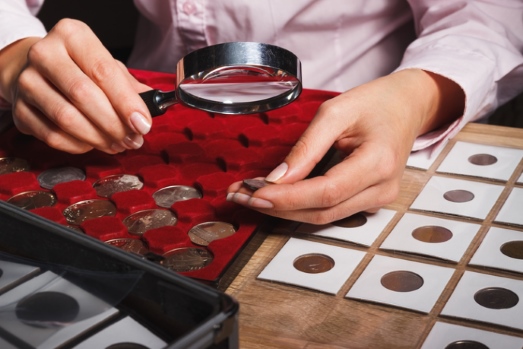 Woman looking at coin through a magnifying glass
