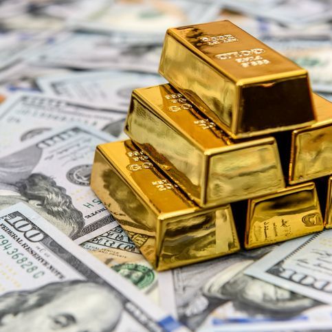 stack of gold bars on several $100 bills