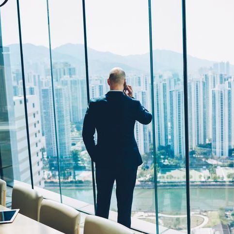 man on cell phone overlooking metropolis with back to the camera